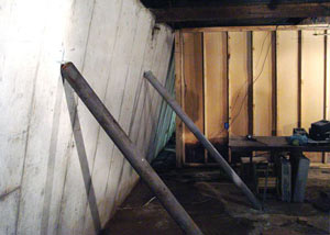A severely tilting foundation wall propped up by steel beams in Rusagonis.