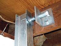 Securing the i-beam system to the top of the floor joist in a foundation wall repair in Summerside.
