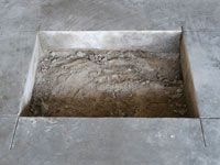 Creating the hole in the garage slab floor during the wall anchor installation in Kentville.